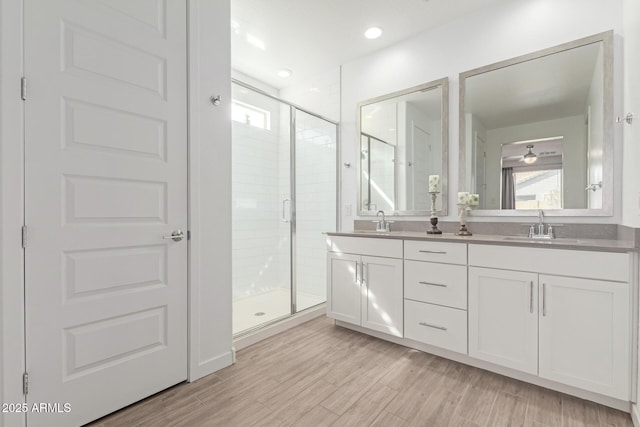 bathroom featuring a healthy amount of sunlight, a stall shower, wood finished floors, and a sink