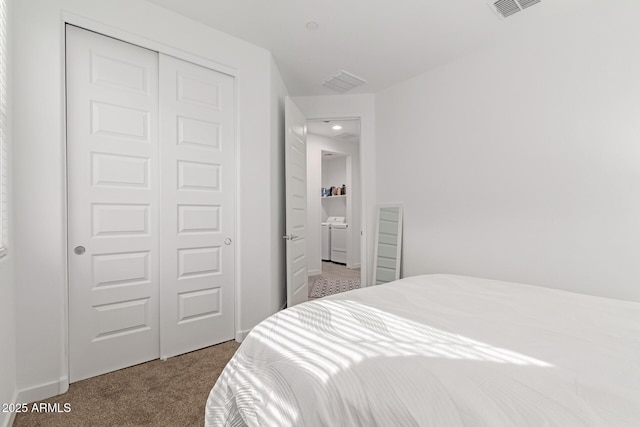 carpeted bedroom with washer and dryer, visible vents, and a closet