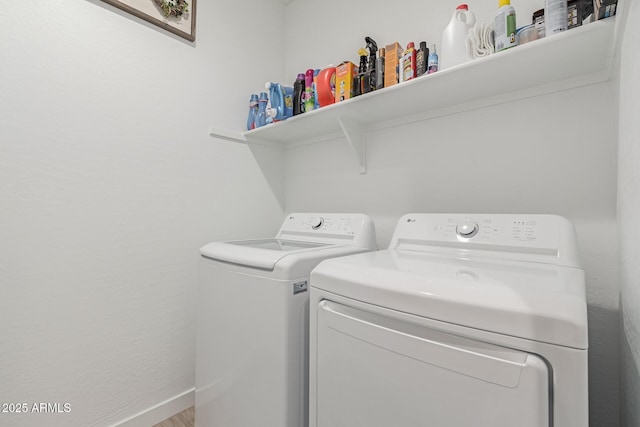 washroom featuring baseboards, separate washer and dryer, and laundry area