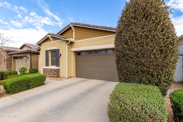 view of front of house with driveway, an attached garage, stucco siding, stone siding, and a tiled roof