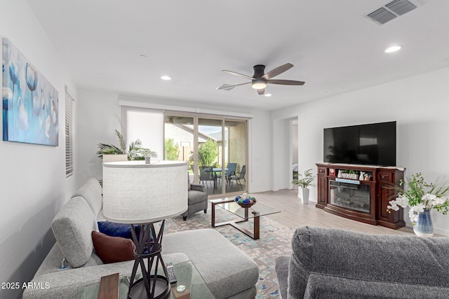 living room featuring wood finished floors, visible vents, recessed lighting, ceiling fan, and a glass covered fireplace