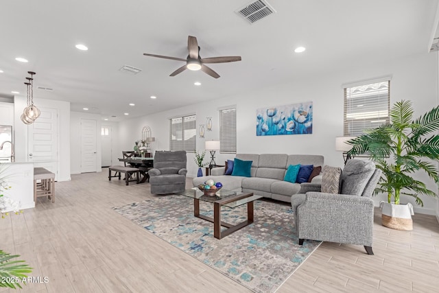 living room featuring baseboards, visible vents, recessed lighting, ceiling fan, and light wood-type flooring