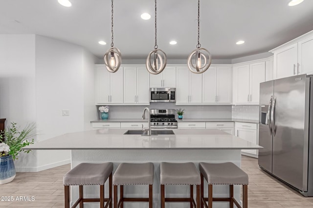 kitchen featuring a breakfast bar, white cabinets, light wood finished floors, and stainless steel appliances