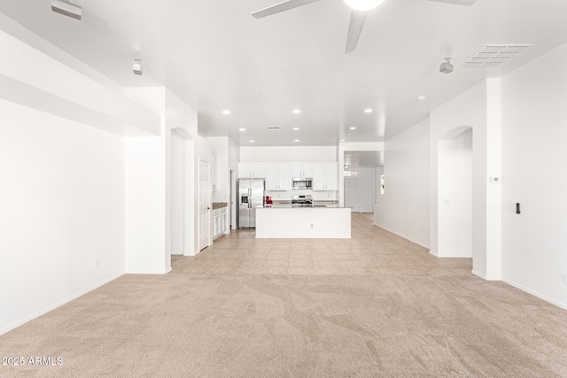 unfurnished living room featuring ceiling fan and light colored carpet