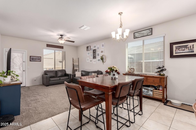 tiled dining space featuring plenty of natural light and ceiling fan with notable chandelier