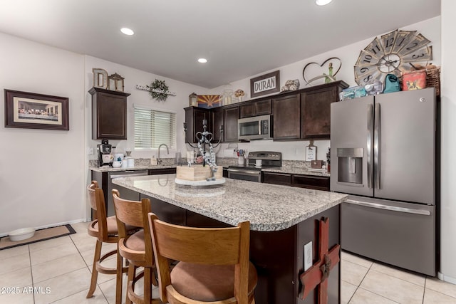 kitchen featuring sink, a center island, dark brown cabinets, light tile patterned floors, and stainless steel appliances