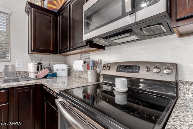 kitchen with light stone counters, dark brown cabinets, and appliances with stainless steel finishes