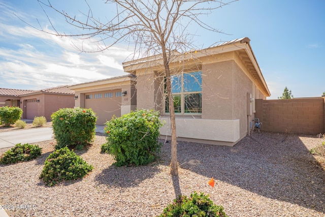 view of front facade featuring stucco siding, an attached garage, and fence