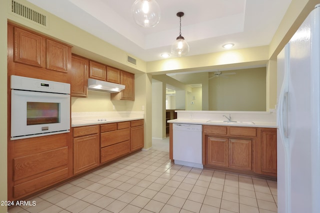 kitchen with hanging light fixtures, white appliances, sink, a tray ceiling, and ceiling fan