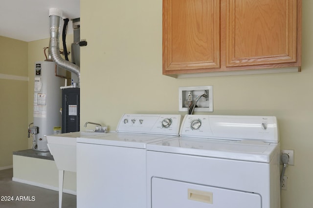 clothes washing area with cabinets, water heater, and washing machine and clothes dryer