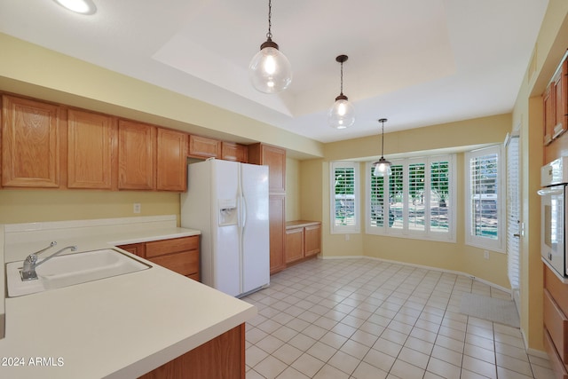 kitchen with decorative light fixtures, white appliances, a raised ceiling, and sink