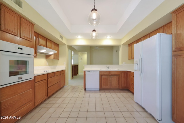 kitchen with white appliances, light tile patterned floors, sink, hanging light fixtures, and a raised ceiling