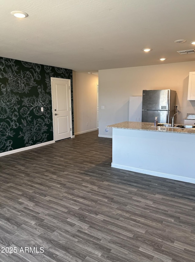 kitchen featuring stainless steel fridge, light stone counters, sink, white cabinets, and dark hardwood / wood-style floors