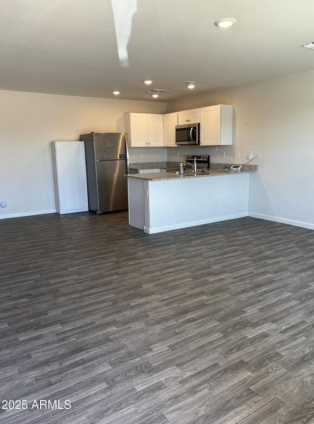 kitchen featuring dark hardwood / wood-style flooring, white cabinetry, kitchen peninsula, and appliances with stainless steel finishes