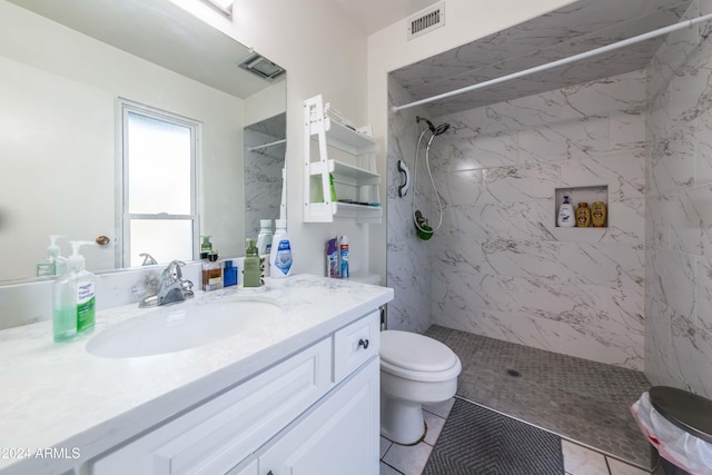 bathroom featuring tiled shower, tile patterned floors, vanity, and toilet