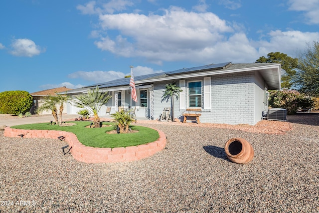 ranch-style home featuring solar panels, a garage, and central air condition unit