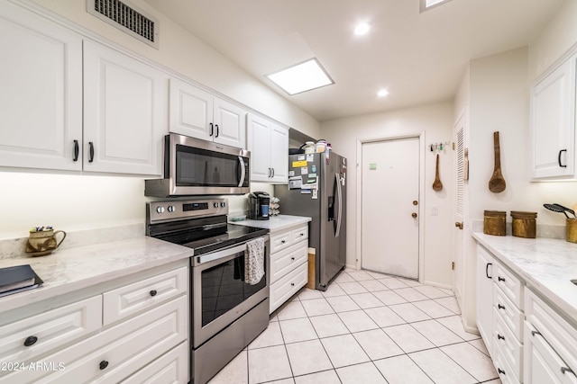 kitchen featuring white cabinets, stainless steel appliances, light stone countertops, and light tile patterned flooring