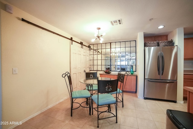 tiled dining room with a barn door and a notable chandelier