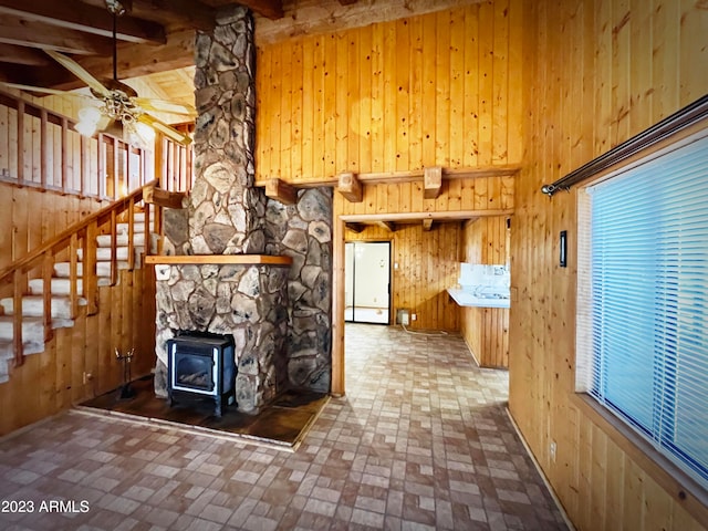 kitchen featuring white fridge, ceiling fan, a wood stove, beamed ceiling, and wooden walls