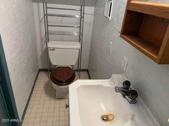 bathroom with toilet, sink, and tile flooring