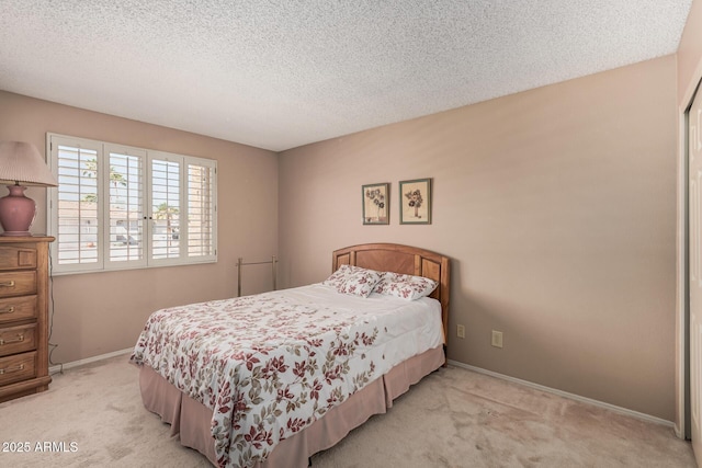 bedroom with baseboards, light colored carpet, and a textured ceiling