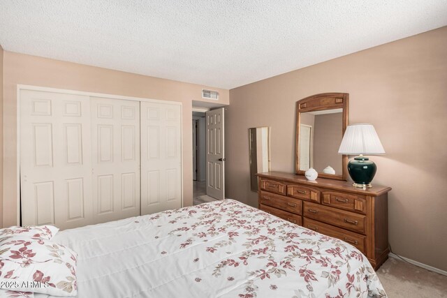 bedroom with a closet, a textured ceiling, visible vents, and light colored carpet