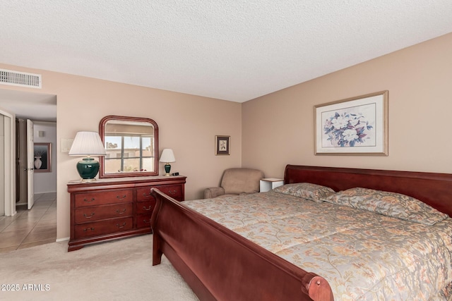 bedroom featuring light carpet, visible vents, and a textured ceiling