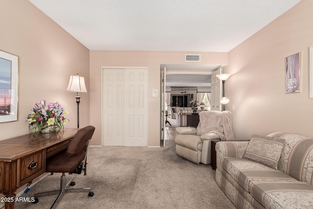 carpeted office space with a textured ceiling and visible vents