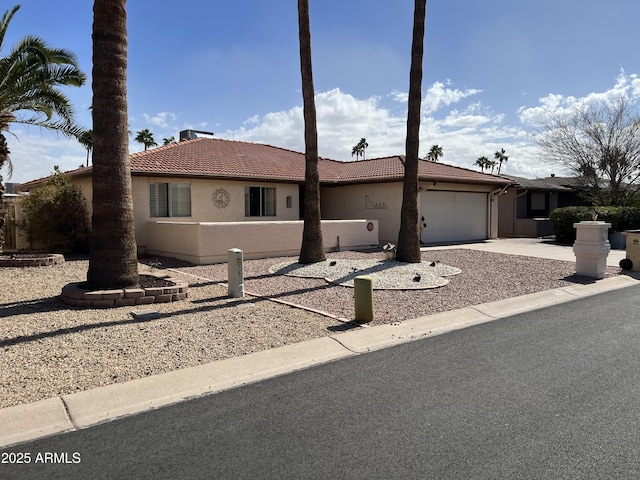 ranch-style home with a tile roof, stucco siding, an attached garage, and driveway