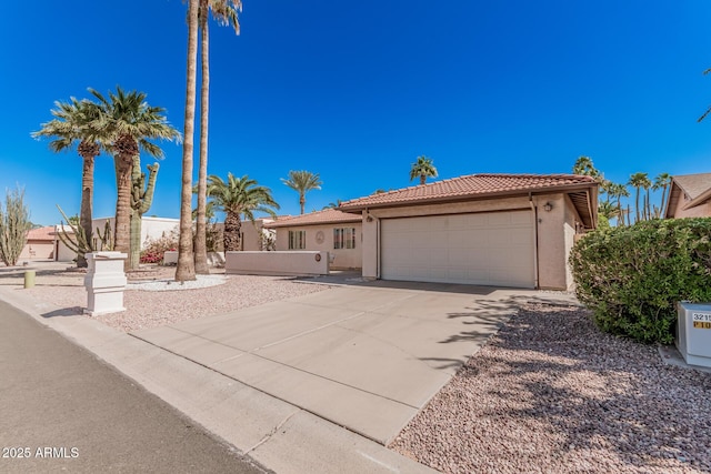 view of front of house with fence, an attached garage, stucco siding, a tile roof, and driveway