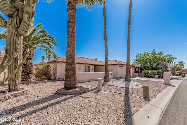 view of front of house featuring stucco siding, an attached garage, a tiled roof, and driveway