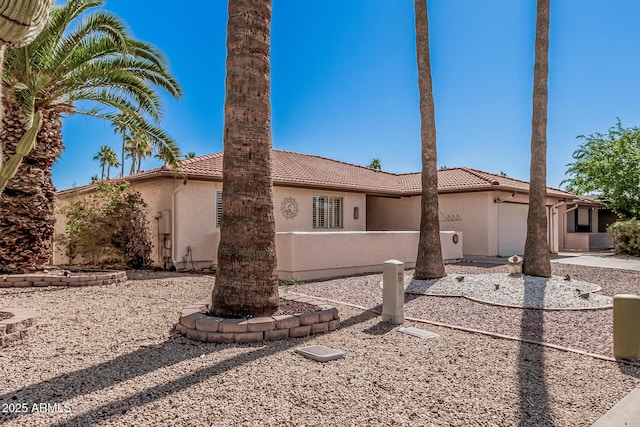 mediterranean / spanish house featuring stucco siding, an attached garage, and a tiled roof