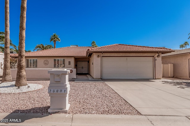 view of front of property with a tile roof, concrete driveway, stucco siding, and an attached garage