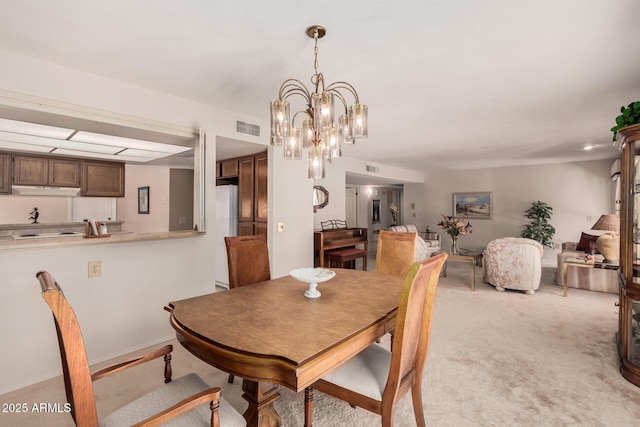 dining area featuring visible vents, a notable chandelier, and light carpet