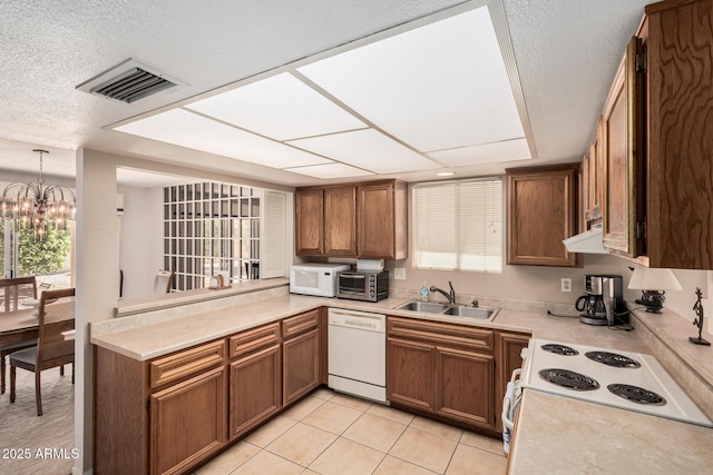kitchen with an inviting chandelier, visible vents, brown cabinets, and white appliances