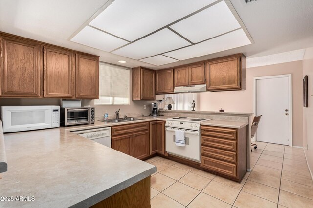 kitchen featuring a sink, brown cabinets, under cabinet range hood, white appliances, and a toaster