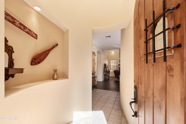 hallway featuring light tile patterned floors, arched walkways, and visible vents