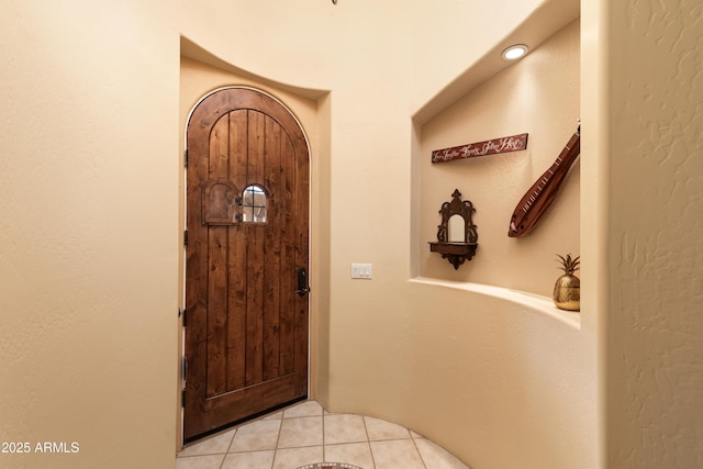 foyer entrance with light tile patterned floors and arched walkways