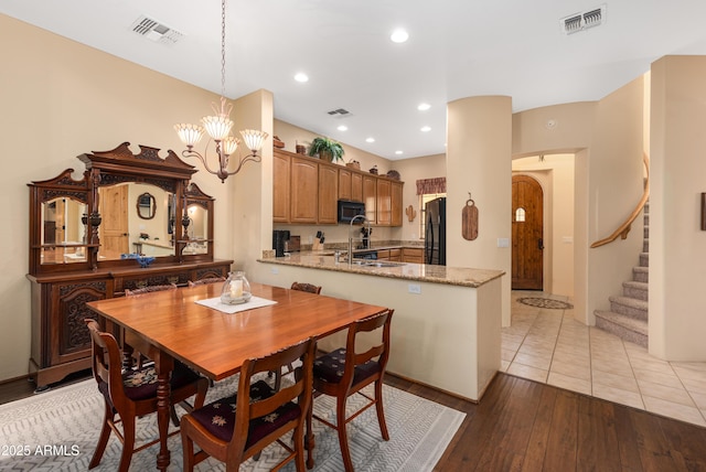 dining area featuring visible vents, stairway, light wood-type flooring, and an inviting chandelier