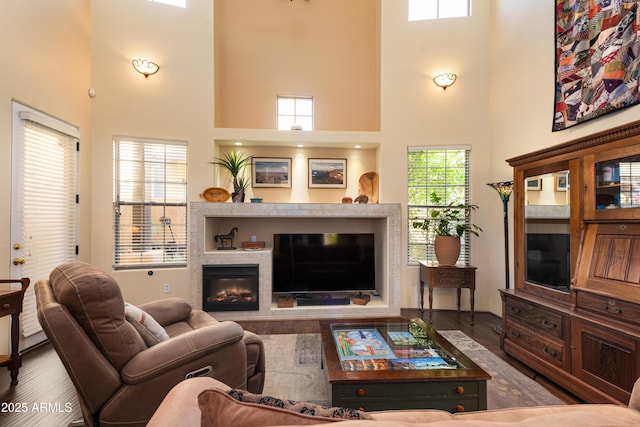 living room featuring wood finished floors, a towering ceiling, and a tile fireplace