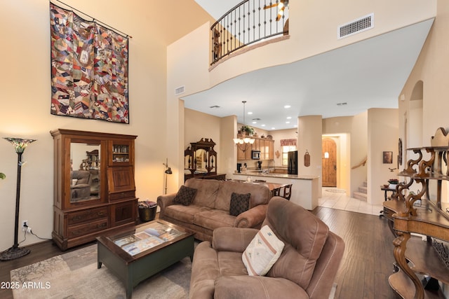 living area featuring visible vents, a high ceiling, stairs, and light wood-style floors