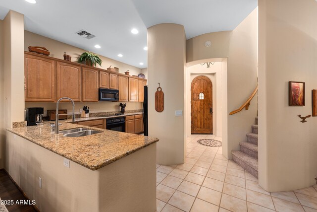 kitchen with light stone countertops, visible vents, recessed lighting, a sink, and black appliances