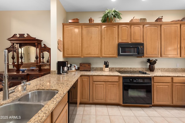 kitchen with black appliances, light stone counters, light tile patterned floors, and a sink