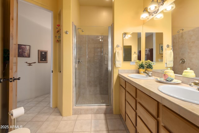 bathroom with a sink, double vanity, a shower stall, and tile patterned flooring