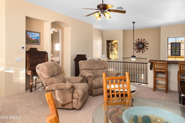 living room featuring a ceiling fan, carpet flooring, arched walkways, and visible vents