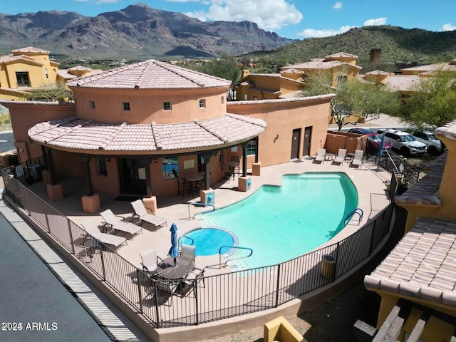 community pool featuring fence, a patio area, and a mountain view