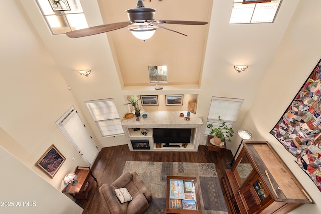 living area with wood finished floors, a towering ceiling, and a ceiling fan