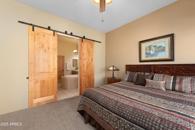 bedroom featuring a barn door, a ceiling fan, carpet floors, and connected bathroom