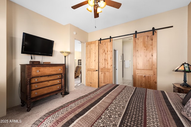 carpeted bedroom featuring a ceiling fan and a barn door