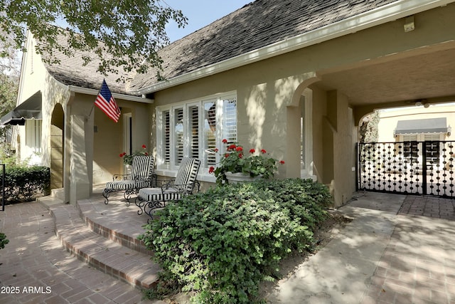 exterior space featuring roof with shingles, a patio, and stucco siding